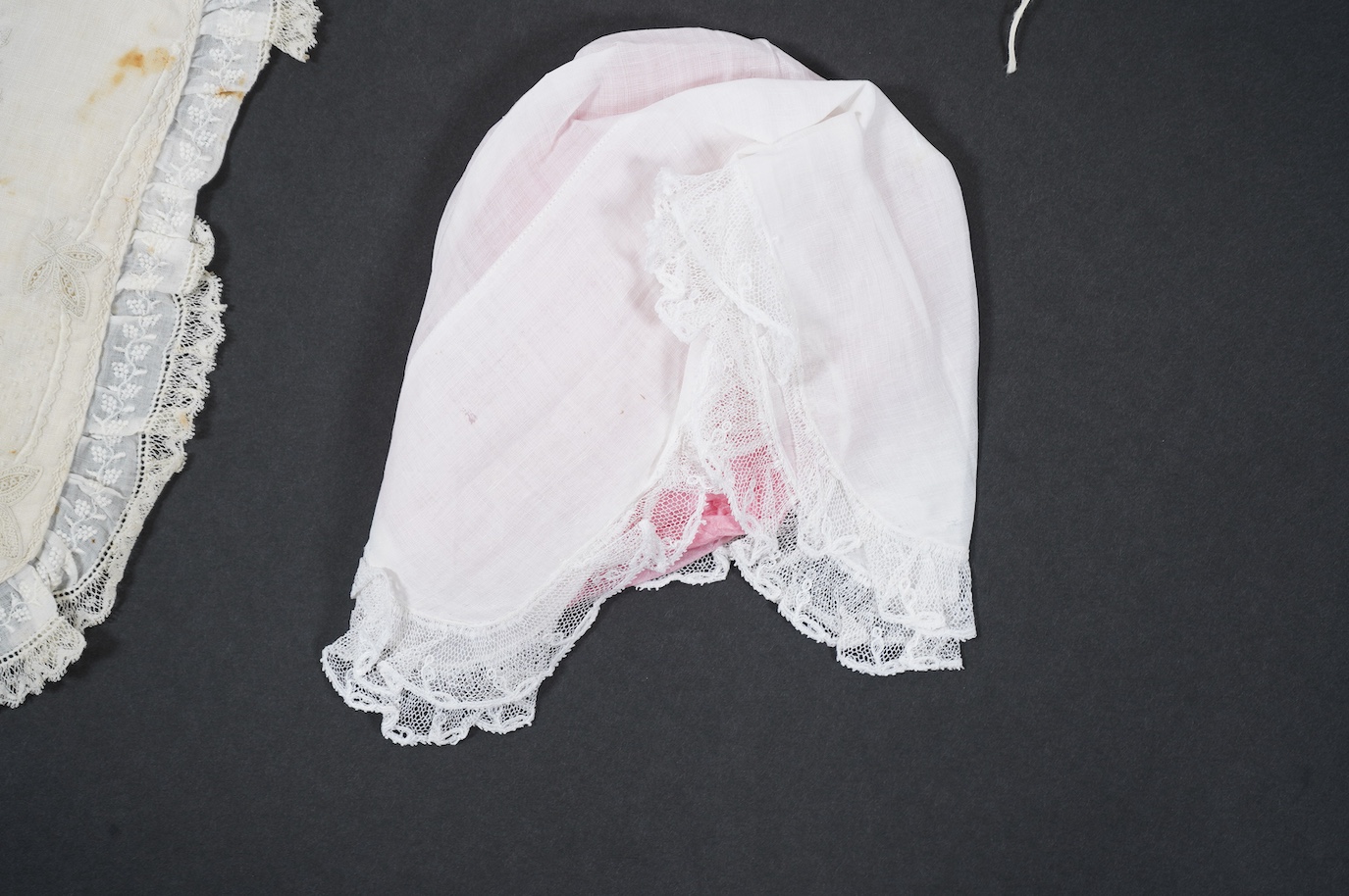 An 18th century Holly Point needle lace panelled linen baby bonnet, an early 19th century white worked baby bib and bonnet and a later 19th century finely ruffed lace bonnet (4). Condition - Holly Point bonnet and bib ha